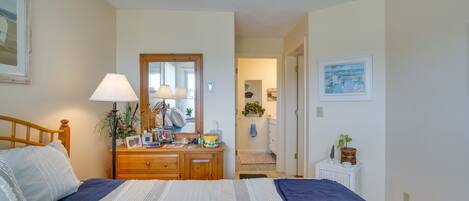 Un dormitorio con cama, cómoda, espejo y un pasillo que lleva a otra habitación.
