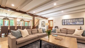 A spacious living room with a large sectional sofa, a wooden coffee table, and a dining area with chairs and a table.