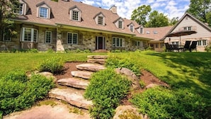 A large stone house with a stone facade, multiple chimneys, and a covered front porch.