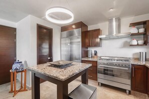 A modern kitchen with stainless steel appliances, a granite countertop, and wooden cabinets. - On 7th Hole Fairway with Access to Beach Clubs! (Punta Mita)