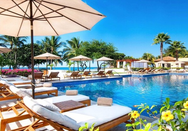 A poolside area with lounge chairs, umbrellas, and a clear view of the ocean. - On 7th Hole Fairway with Access to Beach Clubs! (Punta Mita)