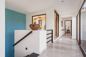 A modern interior with a staircase, a large vase, and a hallway leading to another room. - On 7th Hole Fairway with Access to Beach Clubs! (Punta Mita)