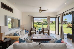 A spacious living room with a large window, a ceiling fan, and a view of a golf course. - On 7th Hole Fairway with Access to Beach Clubs! (Punta Mita)