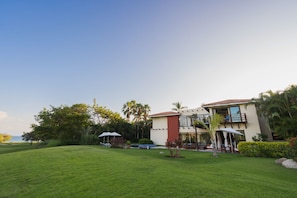 A two-story house with a swimming pool, surrounded by lush greenery and palm trees. - On 7th Hole Fairway with Access to Beach Clubs! (Punta Mita)