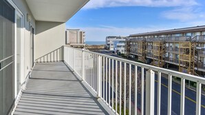 Un balcone con vista su un palazzo a più piani e l'oceano.