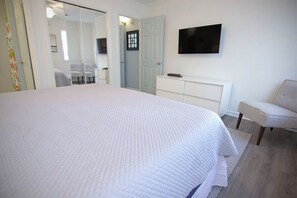 Relax in this serene bedroom with a large bed, flat-screen TV, and comfortable chair.