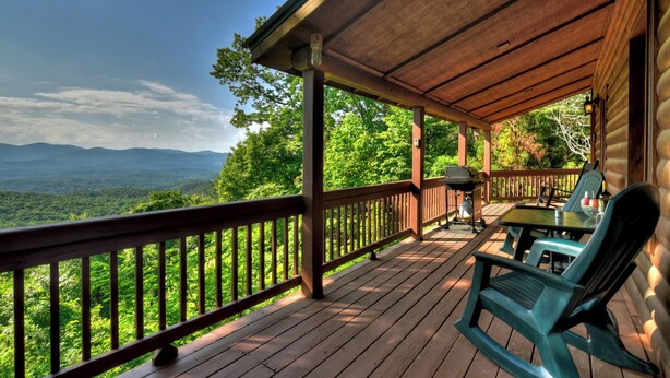 A wooden deck with a view of a forest and mountains.