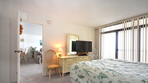 Ein Schlafzimmer mit einem Bett, einem Schminktisch, einem Fernseher und einem Sessel.