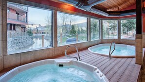 A spa area with two hot tubs and a view of a mountain landscape.