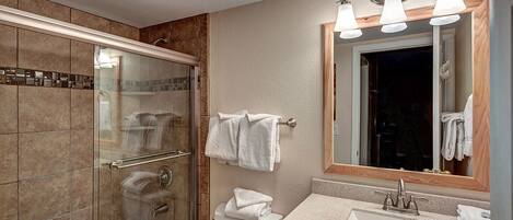 A modern bathroom with a glass-enclosed shower, a vanity with a sink, and a mirror with three lights.