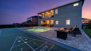 A modern house with a swimming pool, a fire pit, and a shuffleboard court. - Luxurious Villa with Tiki Themed Game Room at Encore (Kissimmee)