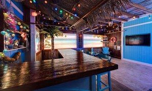 A bar area with a wooden bar, blue chairs, and a view of the beach.