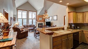 A spacious kitchen with a high ceiling, wooden cabinets, and a central island with a sink. - Ski-in/ski-out, garage, hot tub access! (Breckenridge)