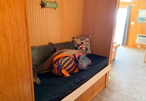 A wooden bunk bed with a dark blue mattress, two colorful fish-shaped pillows, and a wooden wall with a 'BEACH' sign. - Topsail Reef 202 - Ocean Bliss w/ Beach Access! (North Topsail Beach)