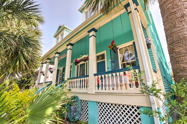 Stunning two-story building with a unique architectural style, featuring a balcony with a lattice railing and lush green surroundings.