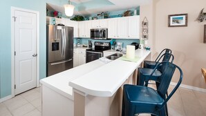 A modern kitchen with white cabinets, stainless steel appliances, and a central island with bar stools. - GD 608: Seas the Gulf - Waves at Your Doorstep! (Fort Walton Beach)