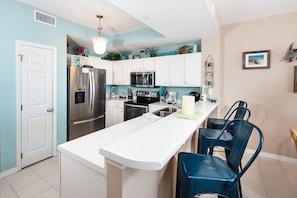 A modern kitchen with white cabinets, stainless steel appliances, and a central island with bar stools.