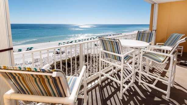 A balcony with white railings, striped chairs, and a view of the beach and ocean. - GD 608: Seas the Gulf - Waves at Your Doorstep! (Fort Walton Beach)