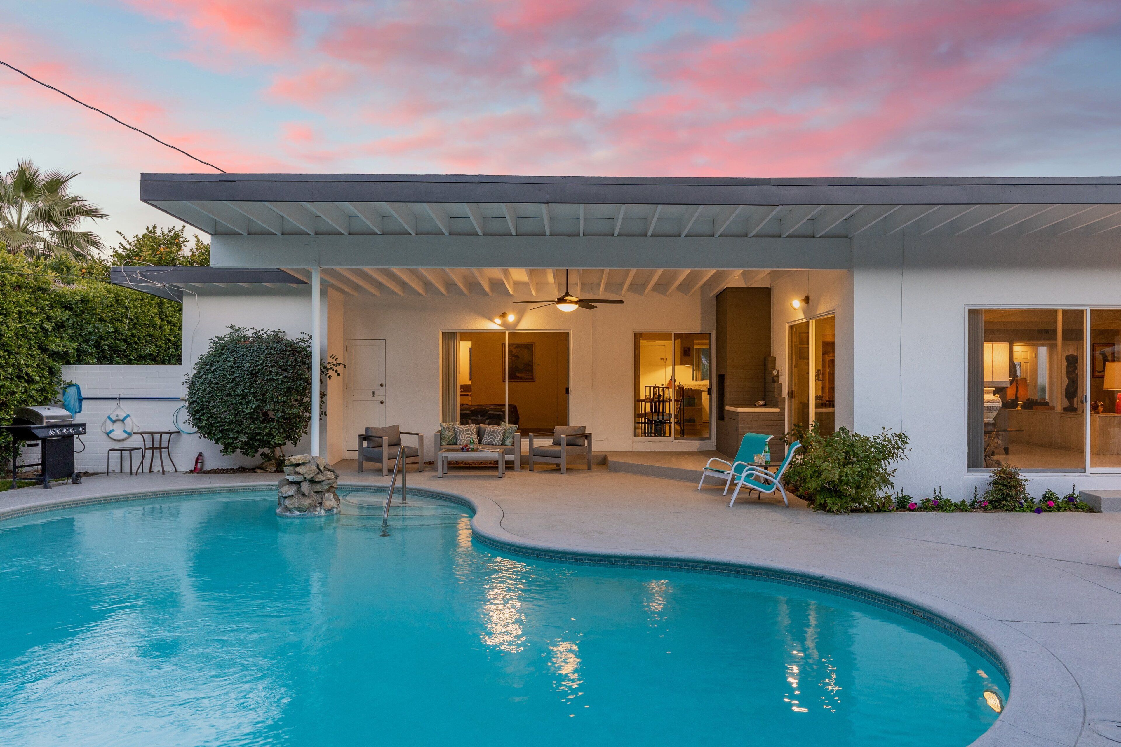 A modern house with a swimming pool, outdoor seating, and a covered patio.
