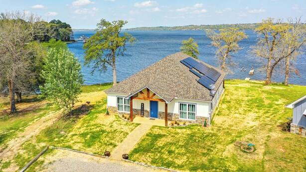 Una casa con techo inclinado, paneles solares y vista a un lago.