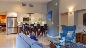 A modern living room with a sofa, a coffee table, and a blue armchair. - Atomic Ranch Heaven - Pool, Spa & Mountain Views (Palm Springs)