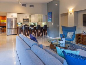 A modern living room with a sofa, a coffee table, and a blue armchair. - Atomic Ranch Heaven - Pool, Spa & Mountain Views (Palm Springs)