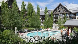 Een resort met een zwembad, omringd door weelderige begroeiing en lodgegebouwen in traditionele bouwstijl.
