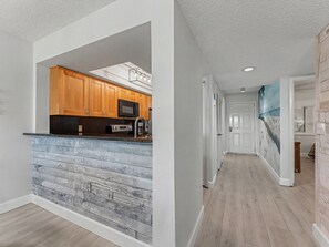 A modern kitchen with wooden cabinets, a black microwave, and a stainless steel sink. - Land's End 202-11, Beach front, Close to Pool! (Treasure Island)
