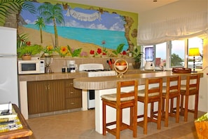 Enjoy a casual dining experience around the central island, featuring a sink and stove, with a microwave, coffee maker, and water dispenser nearby.