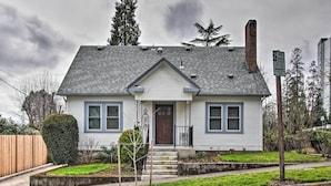 A single-story house with a front porch, a chimney, and a small garden.