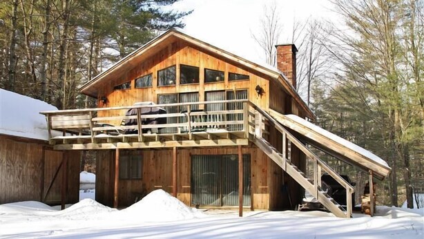 Een houten chalet met balkon en een trap naar de tweede verdieping.
