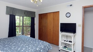 A bedroom with a bed, a TV on a stand, a wooden wardrobe, and a window with curtains. - Quaint, but pristine 2-bedroom condo with free WiFi and an outdoor pool located uptown on the bayside in a peaceful, family-friendly neighborhood! (OCEAN CITY)