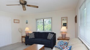 A living room with a ceiling fan, a sofa, a coffee table, and two lamps. - Quaint, but pristine 2-bedroom condo with free WiFi and an outdoor pool located uptown on the bayside in a peaceful, family-friendly neighborhood! (OCEAN CITY)