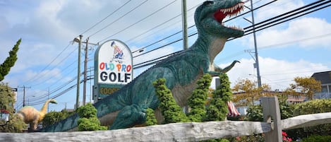Dinosaurus-patsas golfkentän opastekyltin edessä.