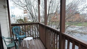 A wooden deck with two green chairs and a small white table. - Quaint, but pristine 2-bedroom condo with free WiFi and an outdoor pool located uptown on the bayside in a peaceful, family-friendly neighborhood! (OCEAN CITY)