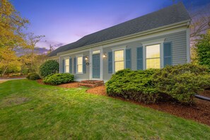 A two-story house with a front porch, a well-maintained lawn, and mature trees. - Walk to Beach, AC, Wifi, Central location (Harwich)