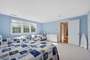 A bedroom with two beds, a white dresser, and a door leading to another room. - Walk to Beach, AC, Wifi, Central location (Harwich)