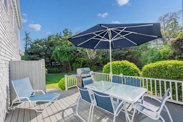 A deck with a grill, two lounge chairs, and a table with an umbrella. - Walk to Beach, AC, Wifi, Central location (Harwich)