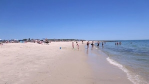 Een strand met mensen die wandelen en zwemmen.