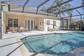 Une piscine avec un patio couvert, des chaises d’extérieur et un ventilateur de plafond.