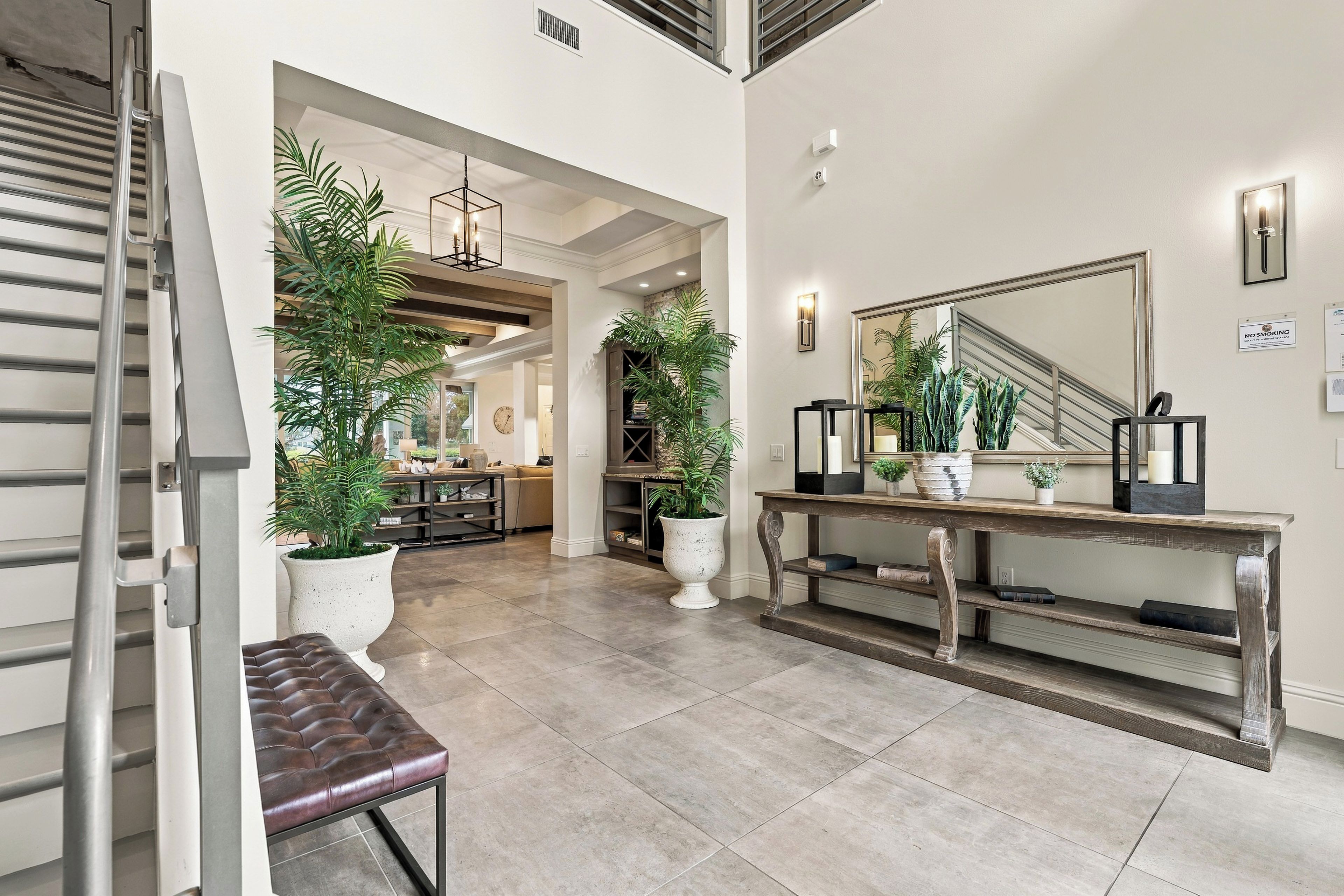 A spacious hallway with a bench, potted plants, a console table, and a large mirror.