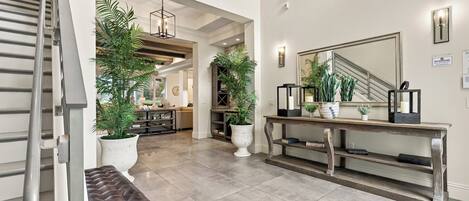 A spacious hallway with a bench, potted plants, a console table, and a large mirror.