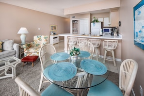 Un espacio habitable compacto con comedor, kitchenette y un sofá con un cojín rojo.
