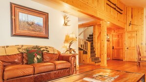 A wooden interior with a leather sofa, a framed picture, a lamp, and a staircase.
