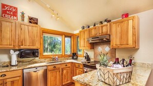 A kitchen with wooden cabinets, a dishwasher, a microwave, a coffee maker, and a fruit basket.