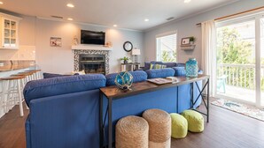 Een moderne woonkamer met een blauwe modulaire bank, een houten salontafel en een open haard.