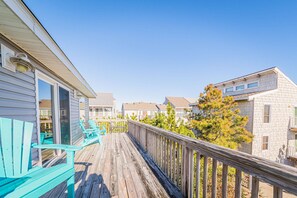 A wooden deck with turquoise Adirondack chairs, a railing, and a view of neighboring buildings. - The Salty Piper - Corolla, Ocean Sands, 100 Yds to Beach, Ocean View, Pets OK, Golf Nearby (Corolla)