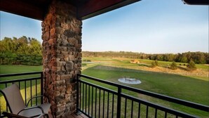 A balcony with stone pillars, chairs, and a view of a golf course. - Two Bedroom Condo @ Spring Brook Resort (Wisconsin Dells)