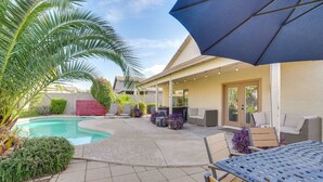 A backyard with a swimming pool, patio furniture, and a covered seating area.