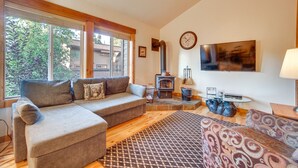 A cozy living room with a sectional sofa, a patterned rug, a fireplace, and a TV mounted on the wall.